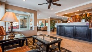A hotel lobby with a glass coffee table, seating area, reception desk, and a ceiling fan. - Best Western Plus Corning Inn (Corning)