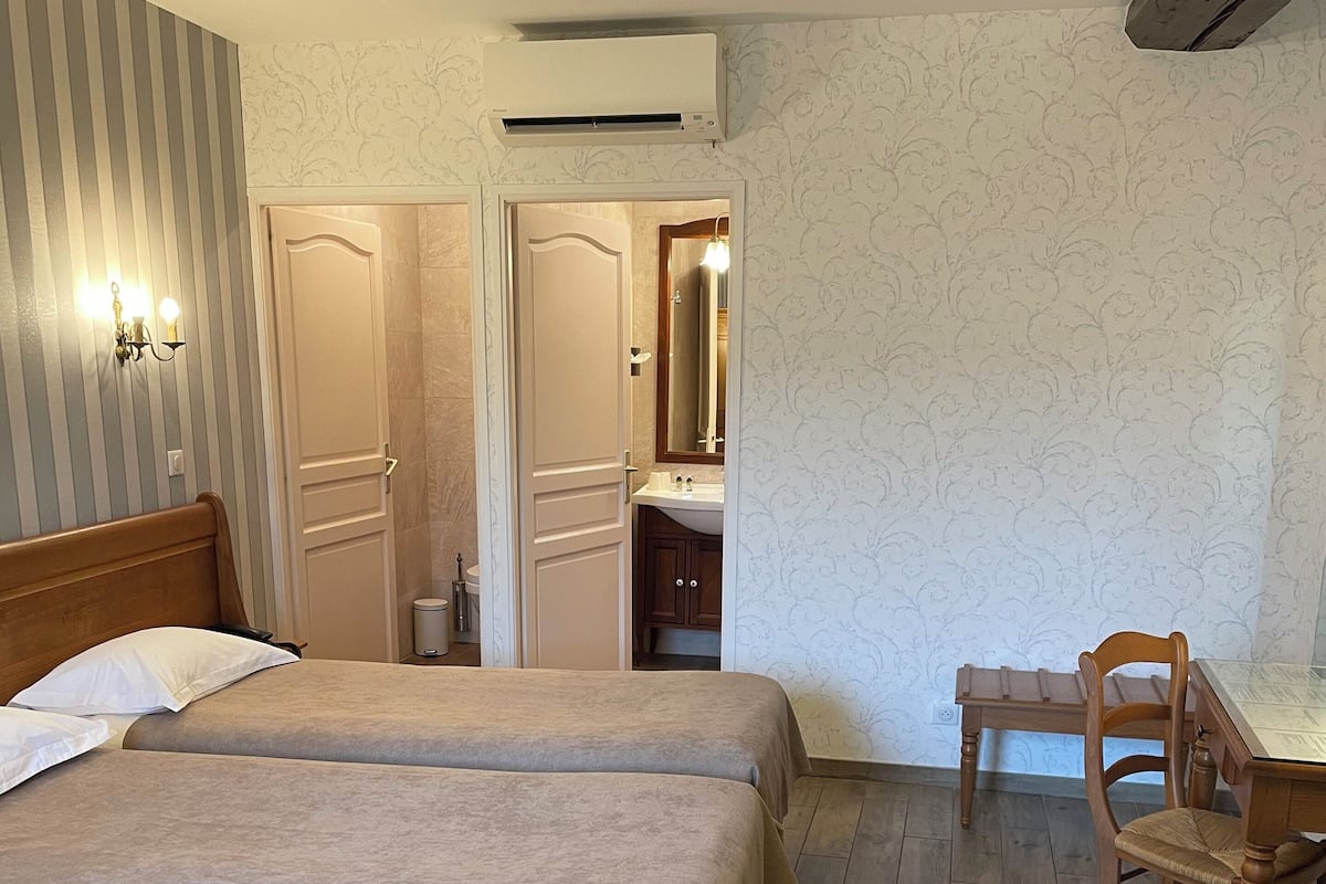 Une chambre d’hôtel avec un lit double, un bureau avec une chaise, un miroir et une armoire.
