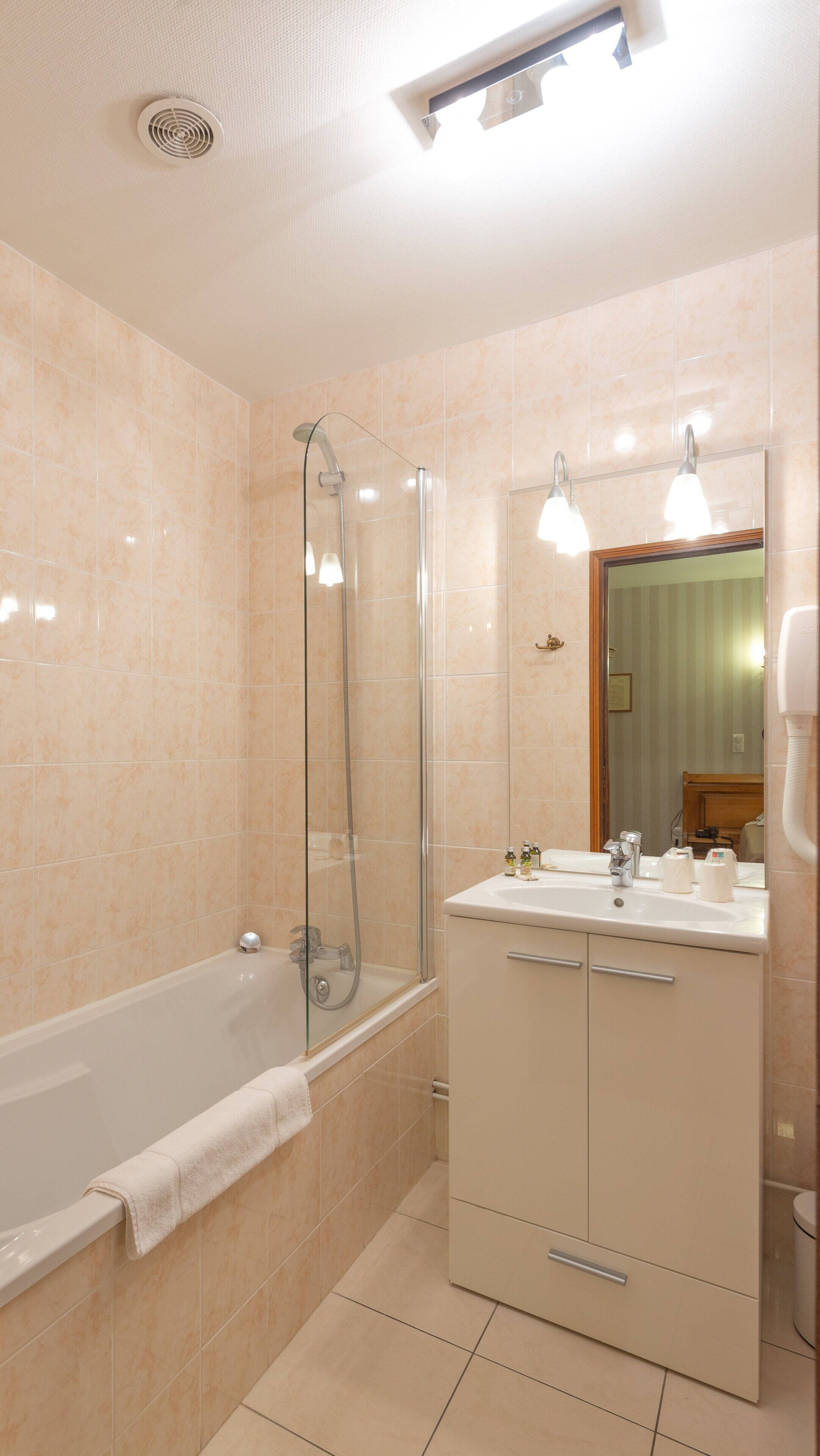 Et moderne badeværelse med badekar, brusebad med glasvægge og et vaskebord med spejl.