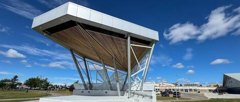 Un pavillon moderne doté d’une structure de toit géométrique, situé dans un espace ouvert sous un ciel dégagé.