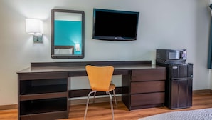 A hotel room with a dark wooden desk, a chair, a flat-screen TV, a microwave, and a small refrigerator. - Motel 6 Rocky Mount, NC (Rocky Mount)