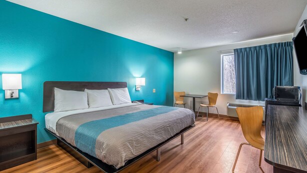 A hotel room with a bed, bedside lamps, a desk, and a chair. - Motel 6 Rocky Mount, NC (Rocky Mount)