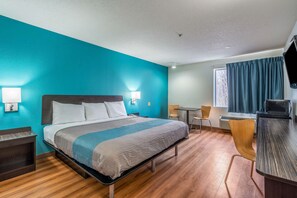 A hotel room with a bed, bedside lamps, a desk, and a chair. - Motel 6 Rocky Mount, NC (Rocky Mount)