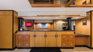 A hotel lobby with a reception desk, a flat-screen TV, and a digital display indicating free Wi-Fi availability. - Red Roof Inn PLUS+ Columbus Downtown-Convention Center (Columbus)