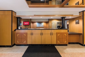 Un vestíbulo de hotel con una recepción, un televisor de pantalla plana y una pantalla digital que muestra la disponibilidad de Wi-Fi gratuito.
