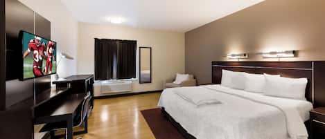 A hotel room with a bed, a desk, a TV, and a window with curtains.