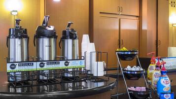 Una estación de desayuno con dispensadores de café, un dispensador de agua y una máquina de café.