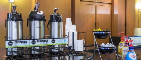 A breakfast station with coffee dispensers, a water dispenser, and a coffee machine.