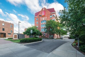 A Red Roof Plus hotel with a brick facade, multiple windows, and a clear sky.