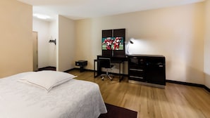 A hotel room with a bed, a desk, a television, and a minibar. - Red Roof Inn PLUS+ Columbus Downtown-Convention Center (Columbus)