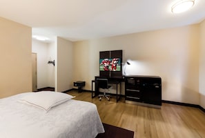 Una habitación de hotel con cama, escritorio, televisor y minibar.