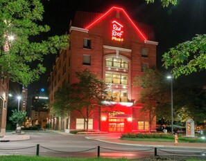 A brick building with a neon sign reading 'Red Roof Plus' at night. - Red Roof Inn PLUS+ Columbus Downtown-Convention Center (Columbus)
