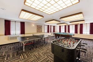 Una habitación con mesa de futbolín, mesa de ping pong y mesa de billar.