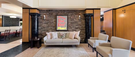 A lobby with a stone wall, a sofa, a chair, and a small table.