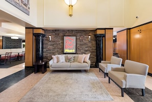 A lobby with a sofa, armchairs, a coffee table, a rug, a fireplace, and a sign that reads "Red Roof Plus". - Red Roof Inn PLUS+ Columbus Downtown-Convention Center (Columbus)