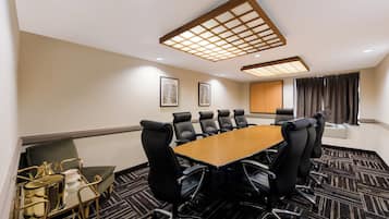 A conference room with a long table, black chairs, and a patterned carpet.