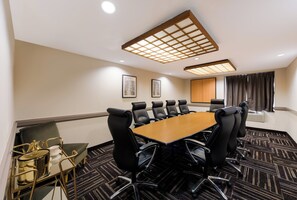 A conference room with a long table, black chairs, and a patterned carpet. - Red Roof Inn PLUS+ Columbus Downtown-Convention Center (Columbus)