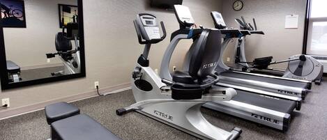 A gym with treadmills, a bench, and a mirrored wall.