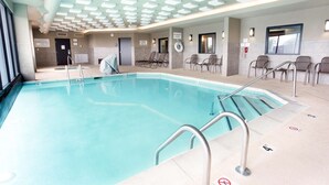 Una piscina con borde de baldosas, barandales metálicos e iluminación empotrada en el techo.