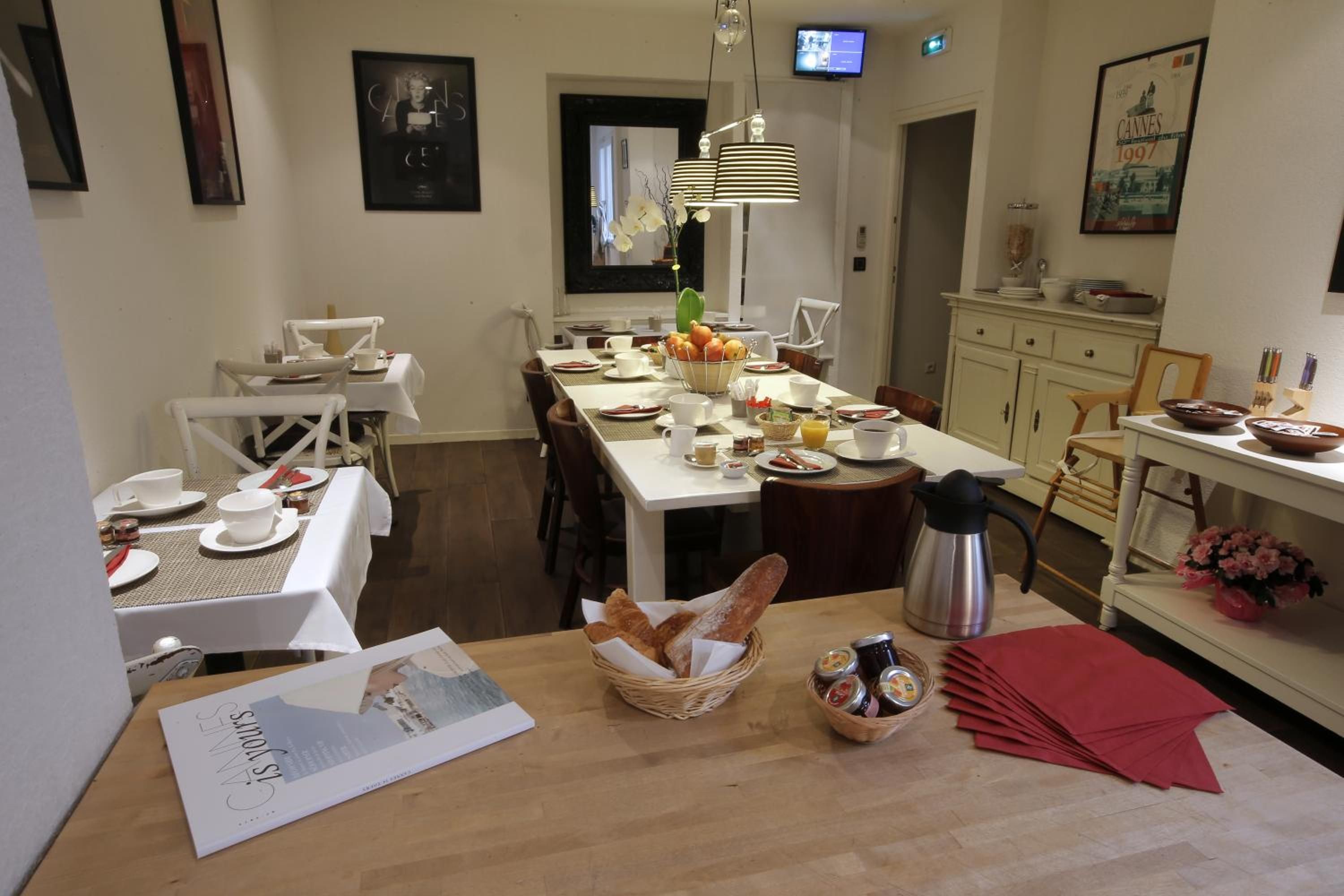 A dining area with a table set for breakfast, including bread, fruit, and condiments.