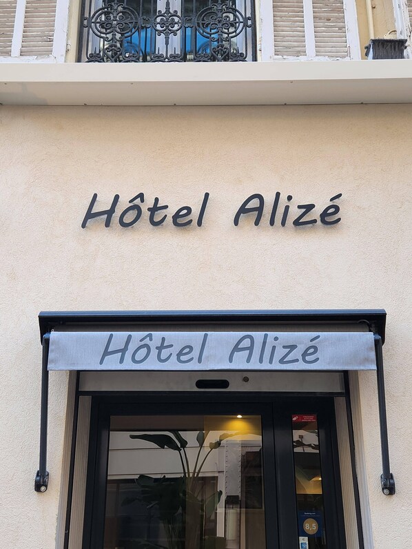 Une enseigne d’hôtel portant le nom « Hôtel Alize » au-dessus de l’entrée.