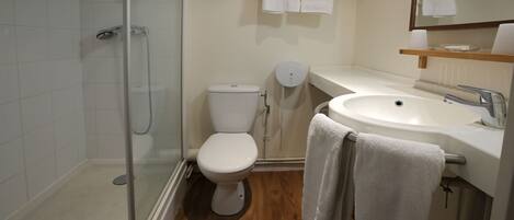 Un baño con cabina de ducha de vidrio, inodoro, lavabo y espejo.