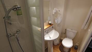 Een badkamer met douche, wastafel, toilet en spiegel.