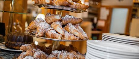 Een gelaagd plateau met verschillende gebakjes, voornamelijk croissants, gepresenteerd op een metalen standaard.
