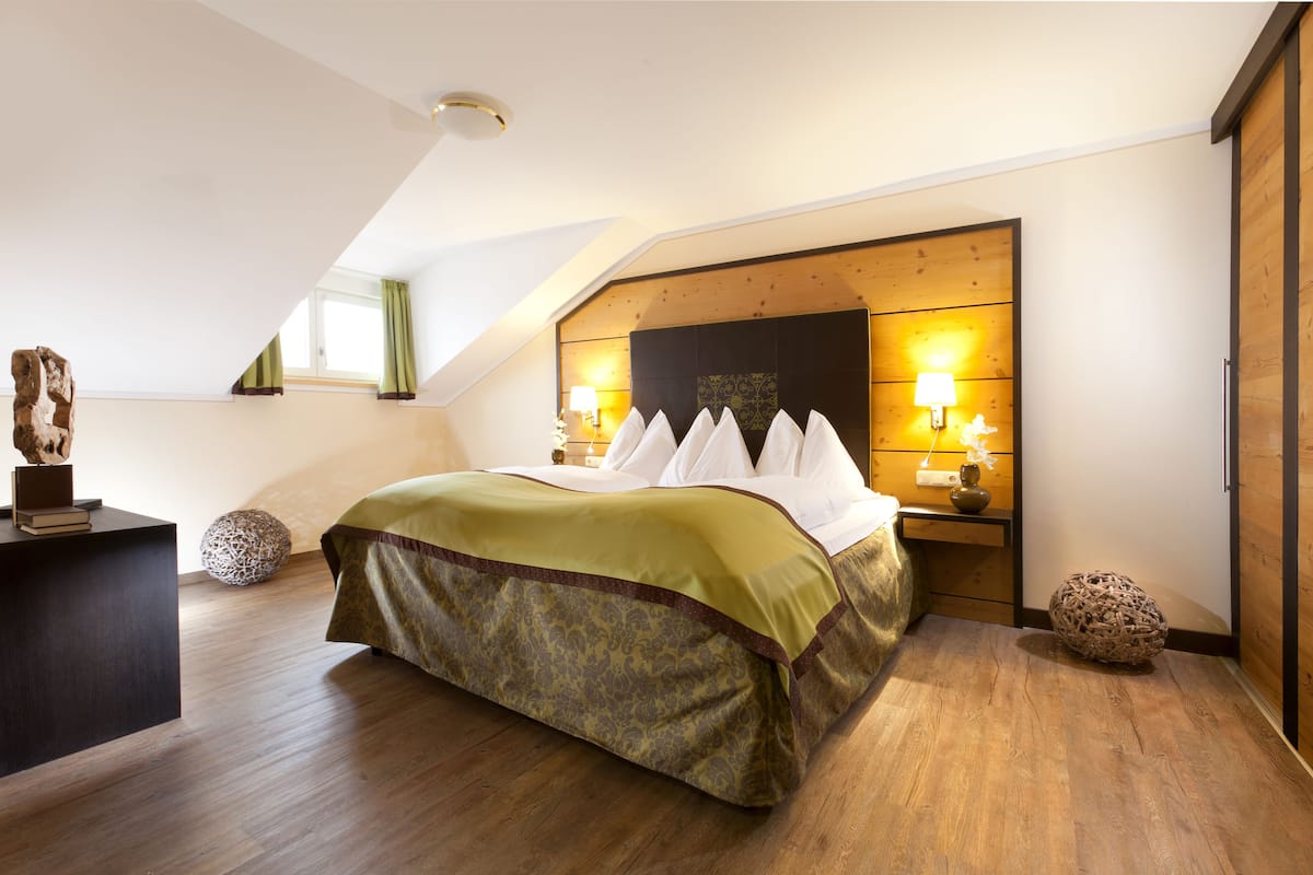 A bedroom with a wooden headboard, a bed with white linens, two bedside lamps, and a small decorative item on the nightstand.