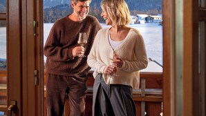 A couple standing by a window with a view of a snowy landscape. - Hotel Sommer Füssen (Fuessen)