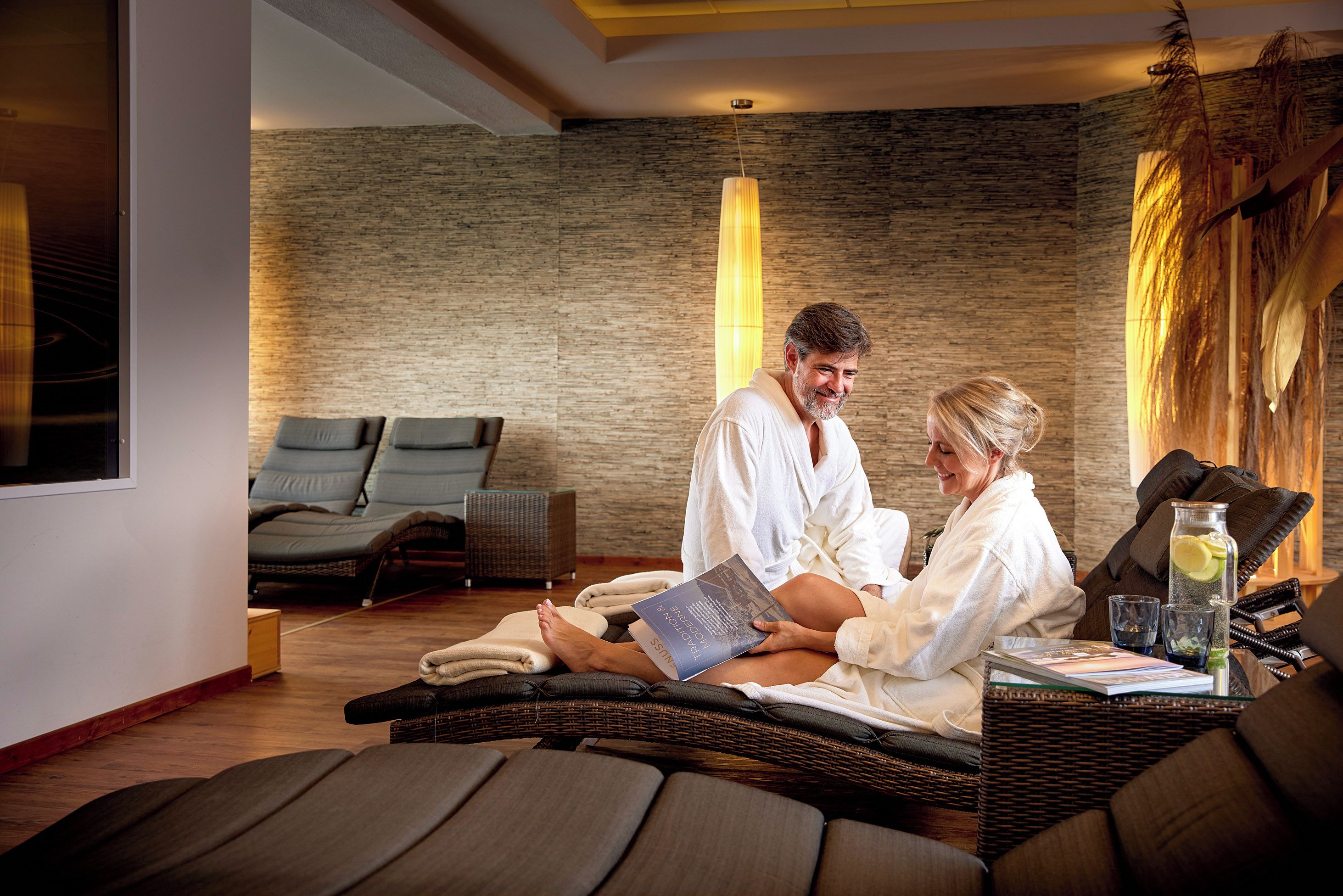 A spa room with a massage table, a massage chair, and a reading area with a book and a glass of water.