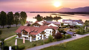 A hotel with multiple buildings, a lake, and mountains in the background. - Hotel Sommer Füssen (Fuessen)