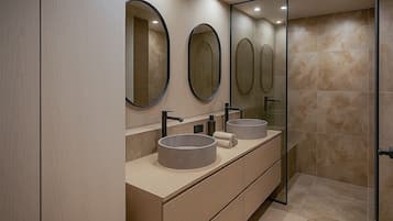 A modern bathroom with two sinks, large mirrors, and a glass shower enclosure.