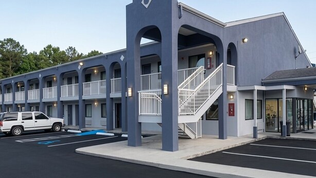 Um motel moderno com átrio central, várias varandas e estacionamento.