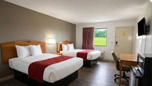 Quarto de hotel com duas camas, uma escrivaninha, uma cadeira e uma televisão.