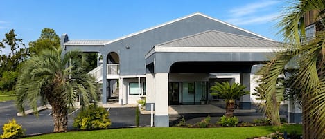 A modern building with a covered parking area, a well-maintained lawn, and a clear sky.