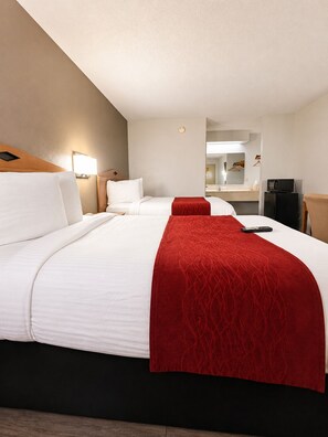 Une chambre d’hôtel avec deux lits, un bureau, un four à micro-ondes et un miroir.