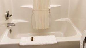 A bathroom with a bathtub, a shower curtain, a towel, and a faucet. - Budget Inn Timmonsville (Timmonsville)