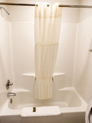 A bathroom with a bathtub, a shower curtain, a towel, and a faucet. - Budget Inn Timmonsville (Timmonsville)