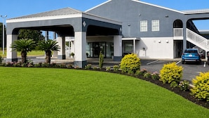 A modern building with a covered entrance, a parking area, and a well-maintained lawn. - Budget Inn Timmonsville (Timmonsville)