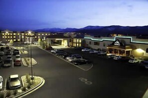 A hotel with a parking lot, a building with a flat roof, and mountains in the background. - Gold Dust West Carson City (Carson City)