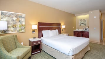 A hotel room with a bed, a chair, a nightstand, a desk, a mirror, and a painting on the wall.