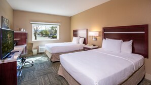 A hotel room with two beds, a desk with a TV, a window with a view of trees, and a lamp on the nightstand. - Gold Dust West Carson City (Carson City)