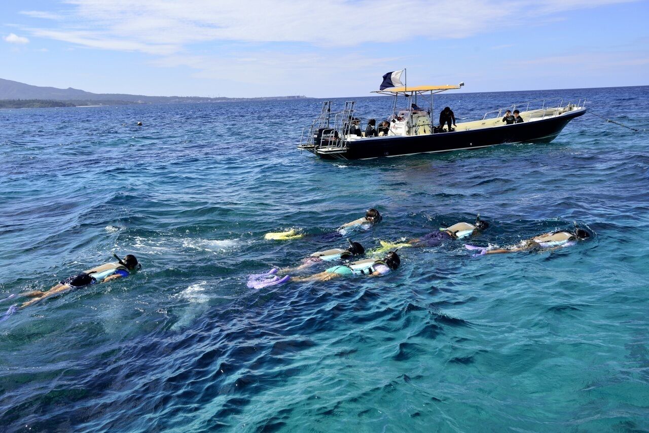 A boat with several people swimming in the water.