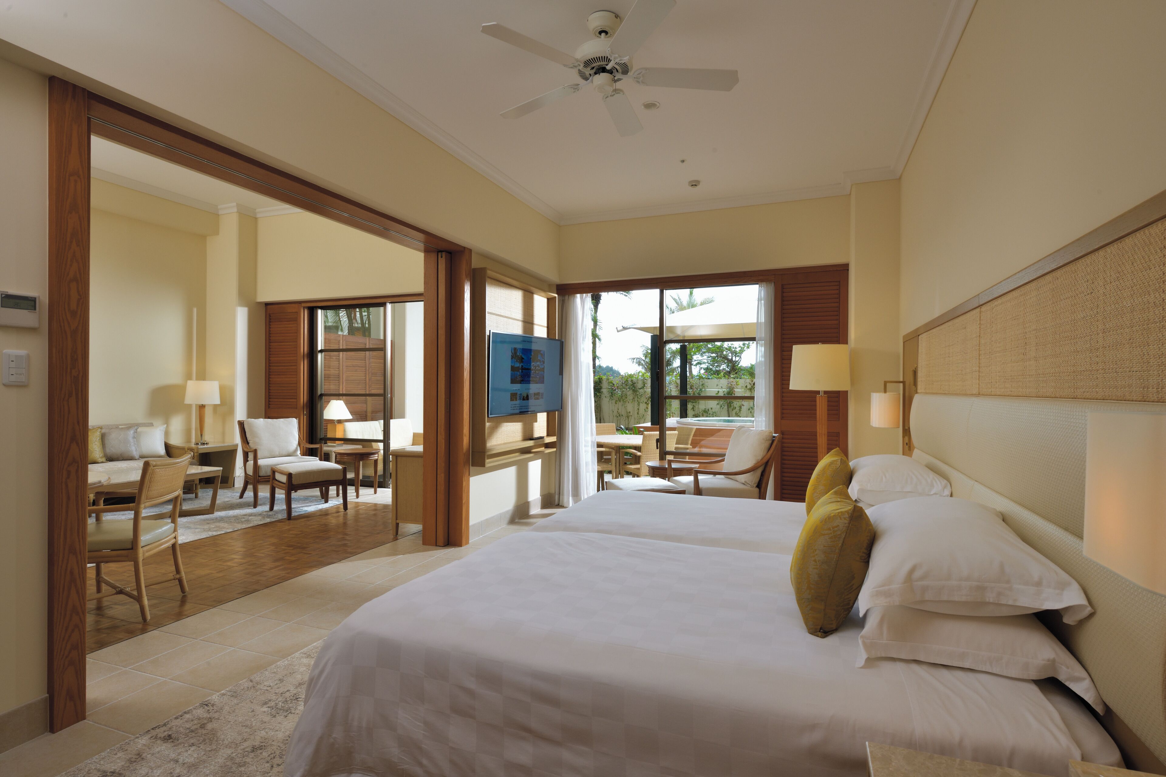A hotel room with two beds, a dining area, and a view of the outdoors.