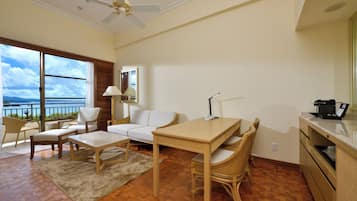 A spacious living area with a wooden floor, a white sofa, a dining table, and a kitchen area.