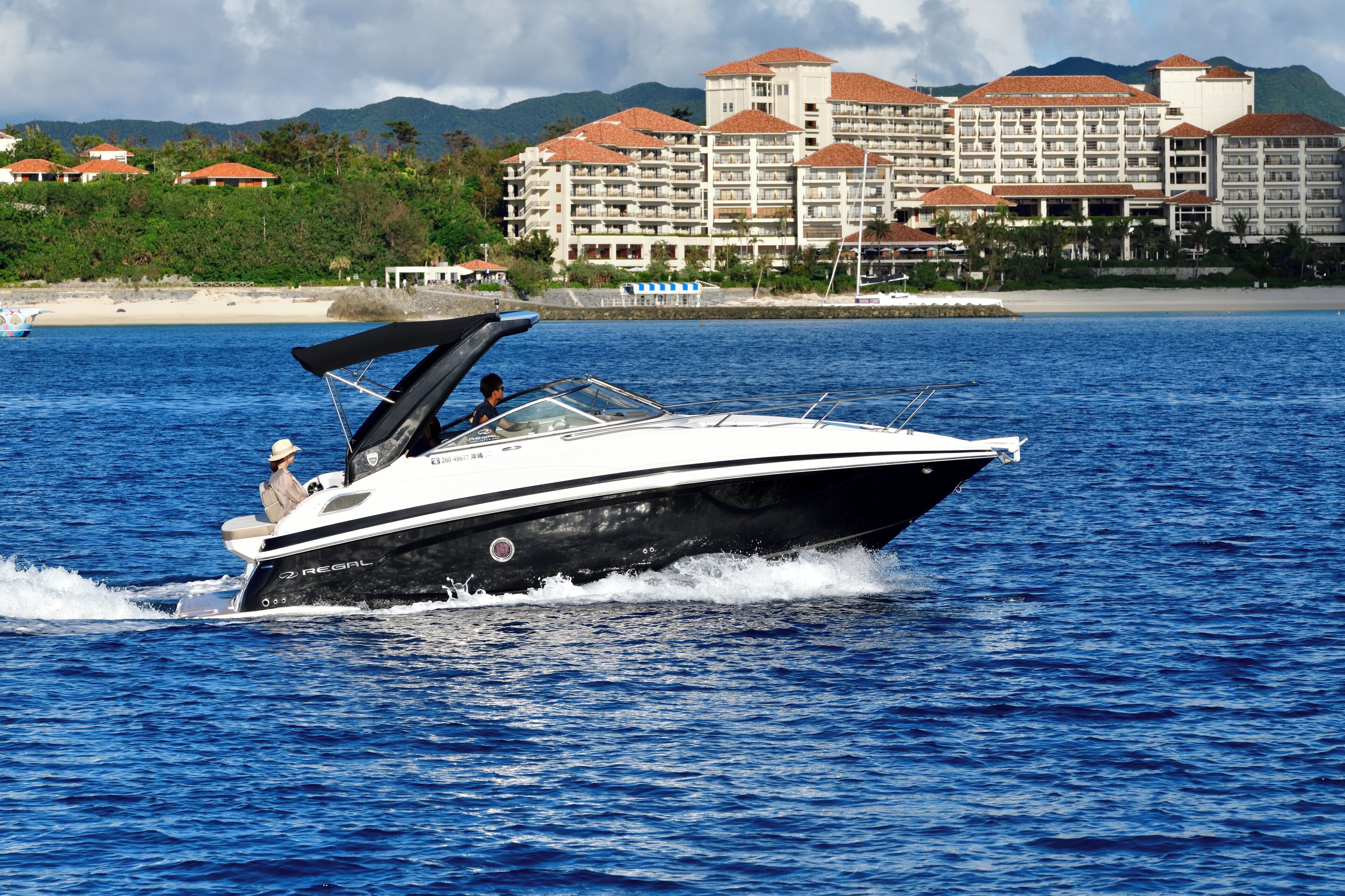 A speedboat on a body of water with a resort hotel in the background.