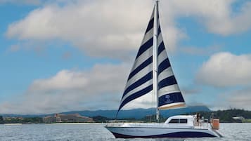 A sailboat named 'The Busena Terrace' on calm waters with a clear sky and distant mountains.