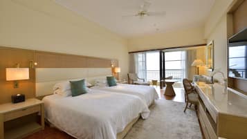 A hotel room with two beds, a desk, a chair, a TV, and a balcony with a view.