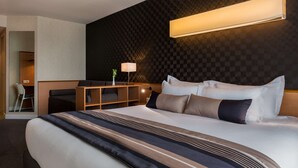 Une chambre d’hôtel avec un grand lit, un bureau et une chaise.